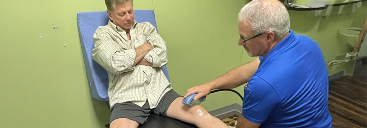 A clinician performs targeted shockwave therapy on a patient’s knee to help reduce pain and improve mobility.